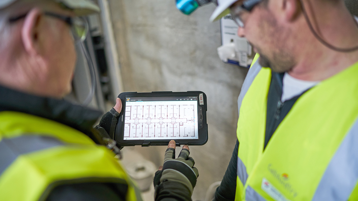 2 people on site looking at a tablet screen 