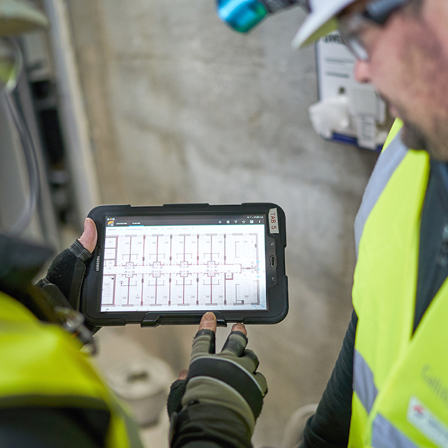2 people on site looking at a tablet screen 