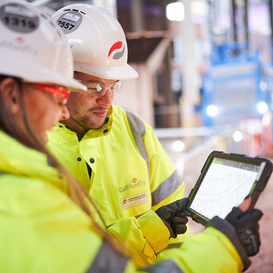 2 people on site looking at a tablet screen 