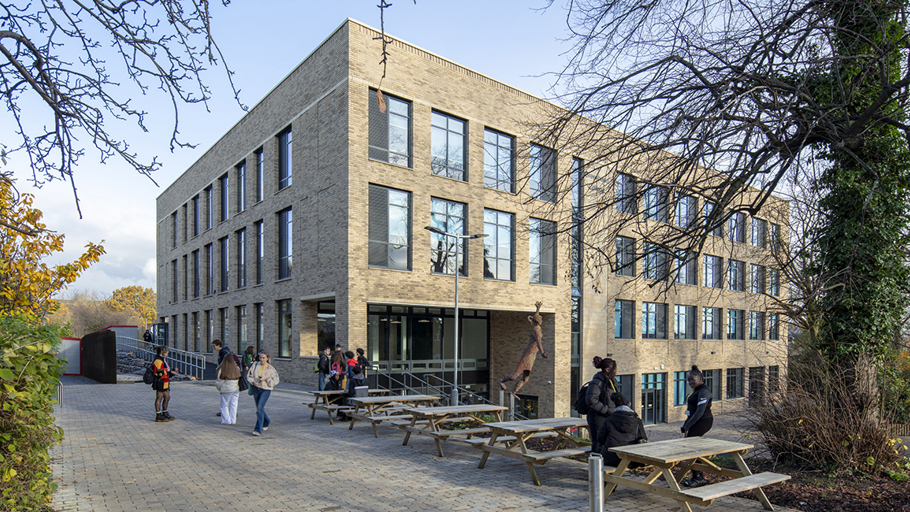 Greenhead College sixth form building. People walking on a brick walkway in front of a building.