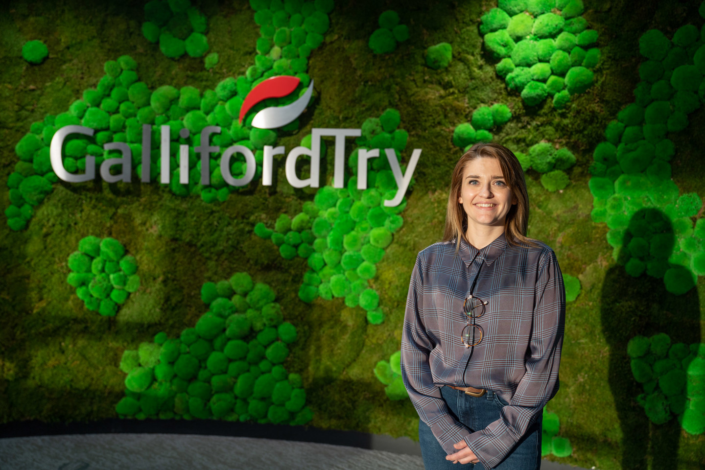 someone stood next to green wall with logo 